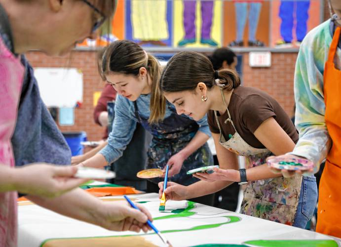 Lucia Flajnik-Palladino, 13, right, and Adelaide Amias, 13, paint one of 52 mural panels to help create a 1,500-square-foot mural for JFK Middle School during a community painting party Saturday afternoon in the school cafeteria.