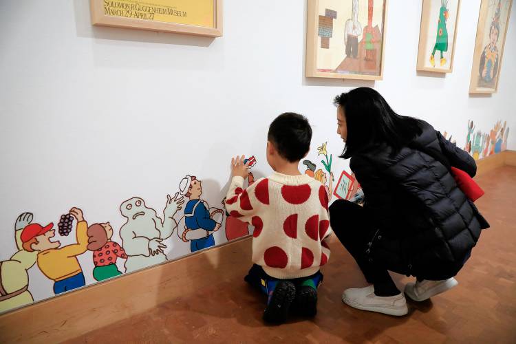 Siun Kim, 6, and his mother, Soojoo Kim, get a close-up look at artwork on the gallery wall at “Kid in a Candy Store,” a new exhibit at the Eric Carle Museum in Amherst.
